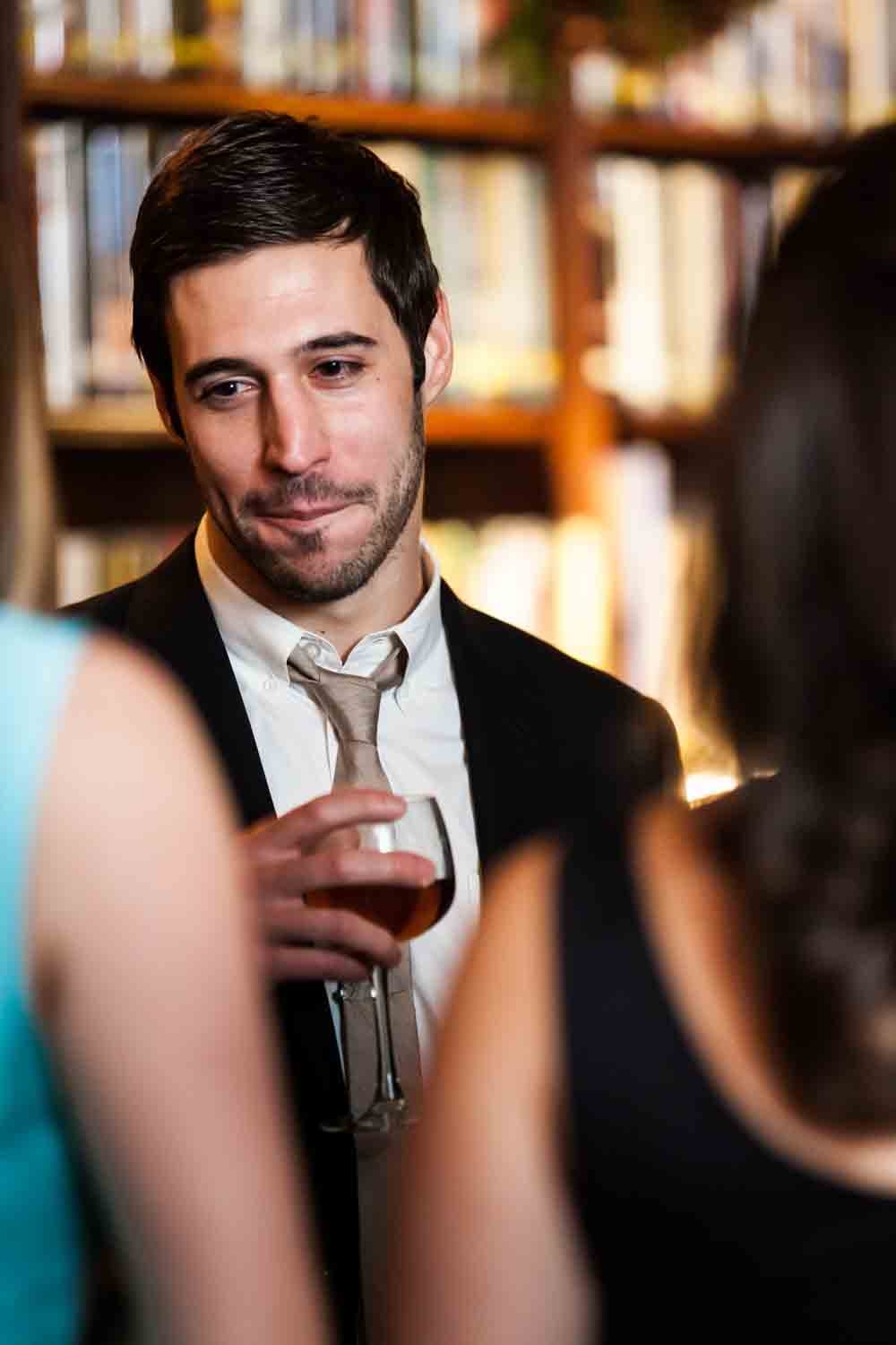 Man holding wine glass and listening to guests