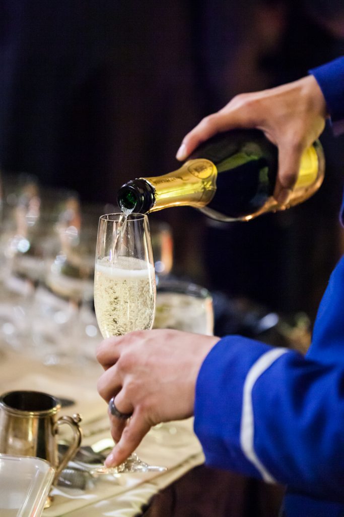 Close up of waiter pouring champagne into a glass