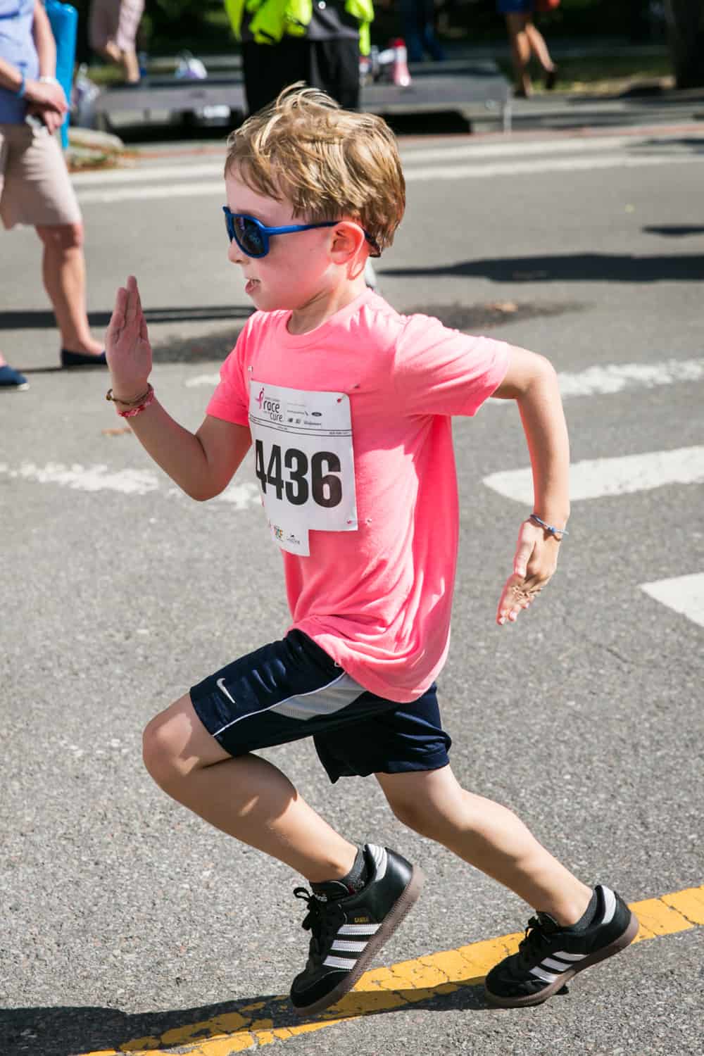NYC Race for the Cure photos of young boy in sunglasses crossing finish line
