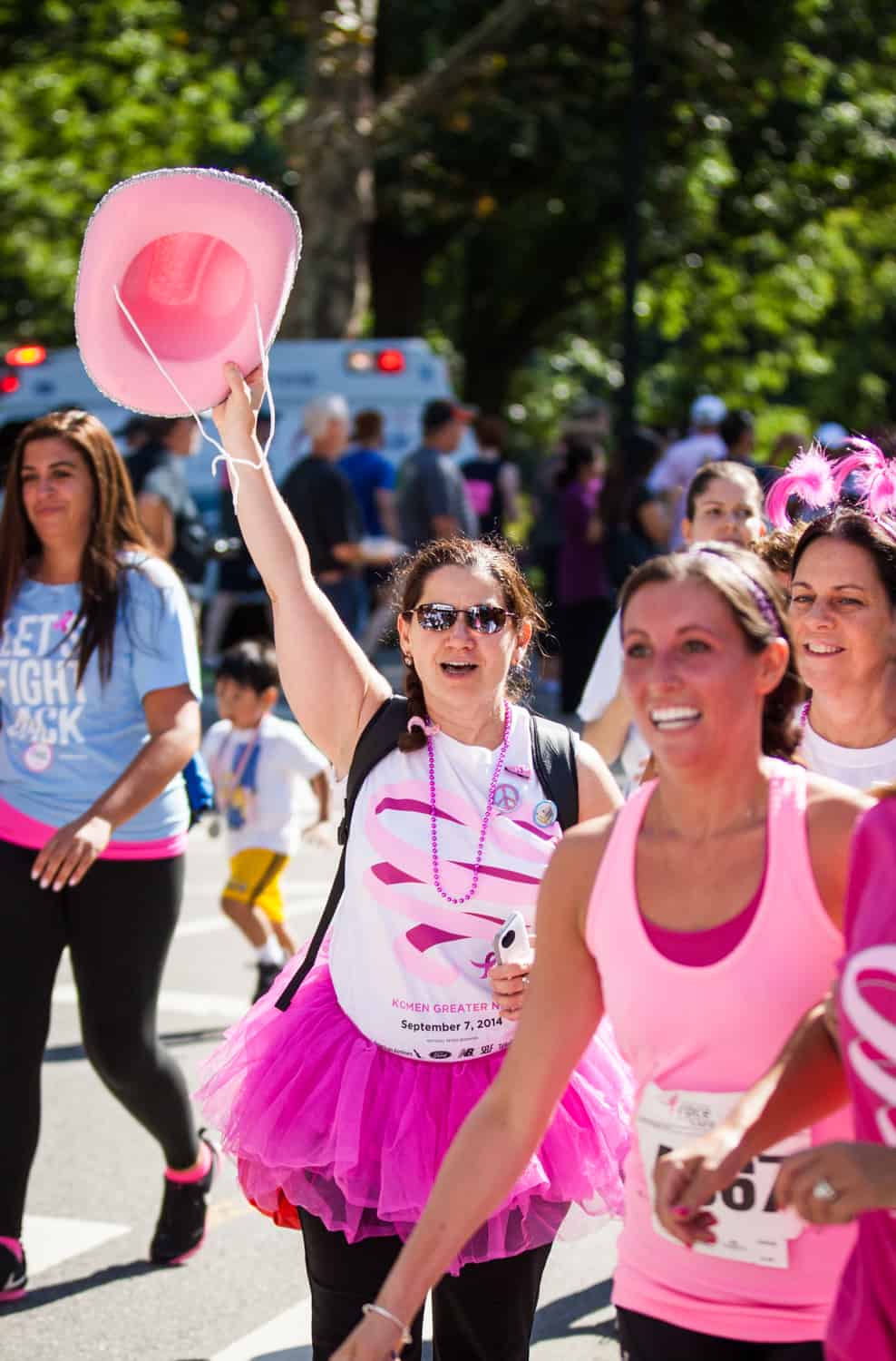 NYC Race for the Cure photos of woman crossing finish line with pink hat in air