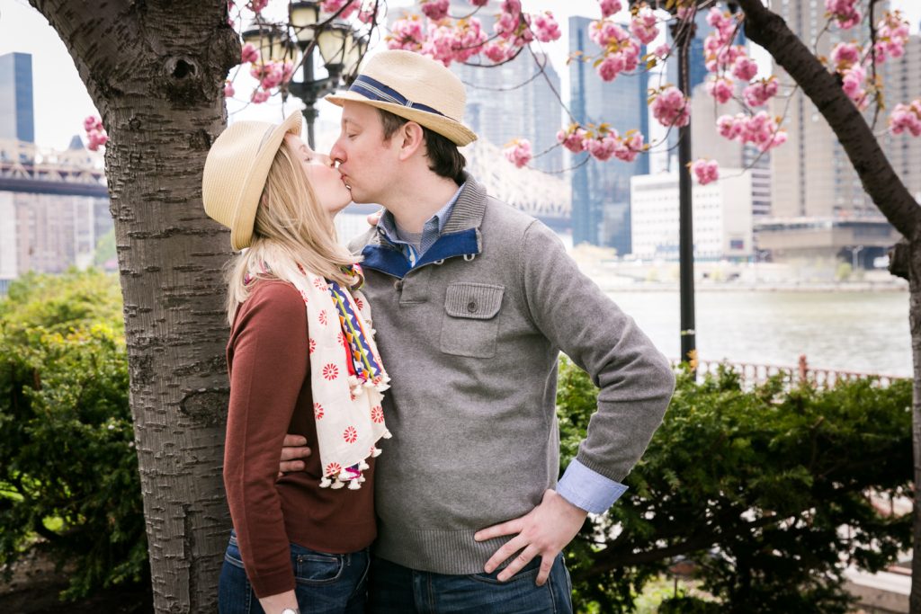 Couple kissing under cherry blossom tree during a Roosevelt Island engagement portrait session
