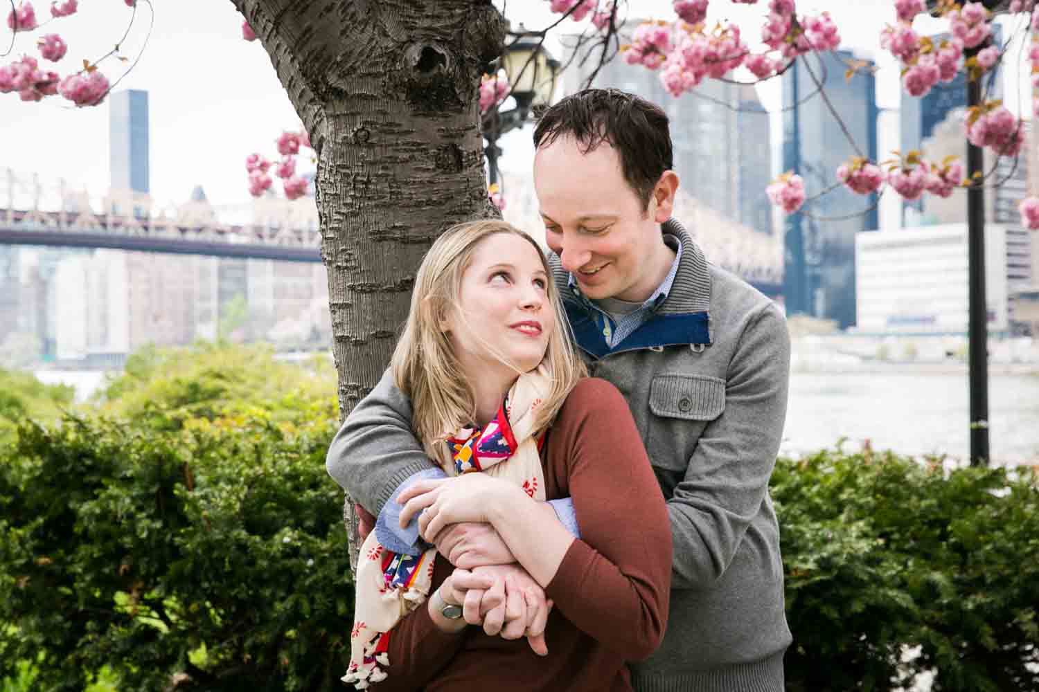 Couple standing under cherry blossom tree during a Roosevelt Island engagement portrait session