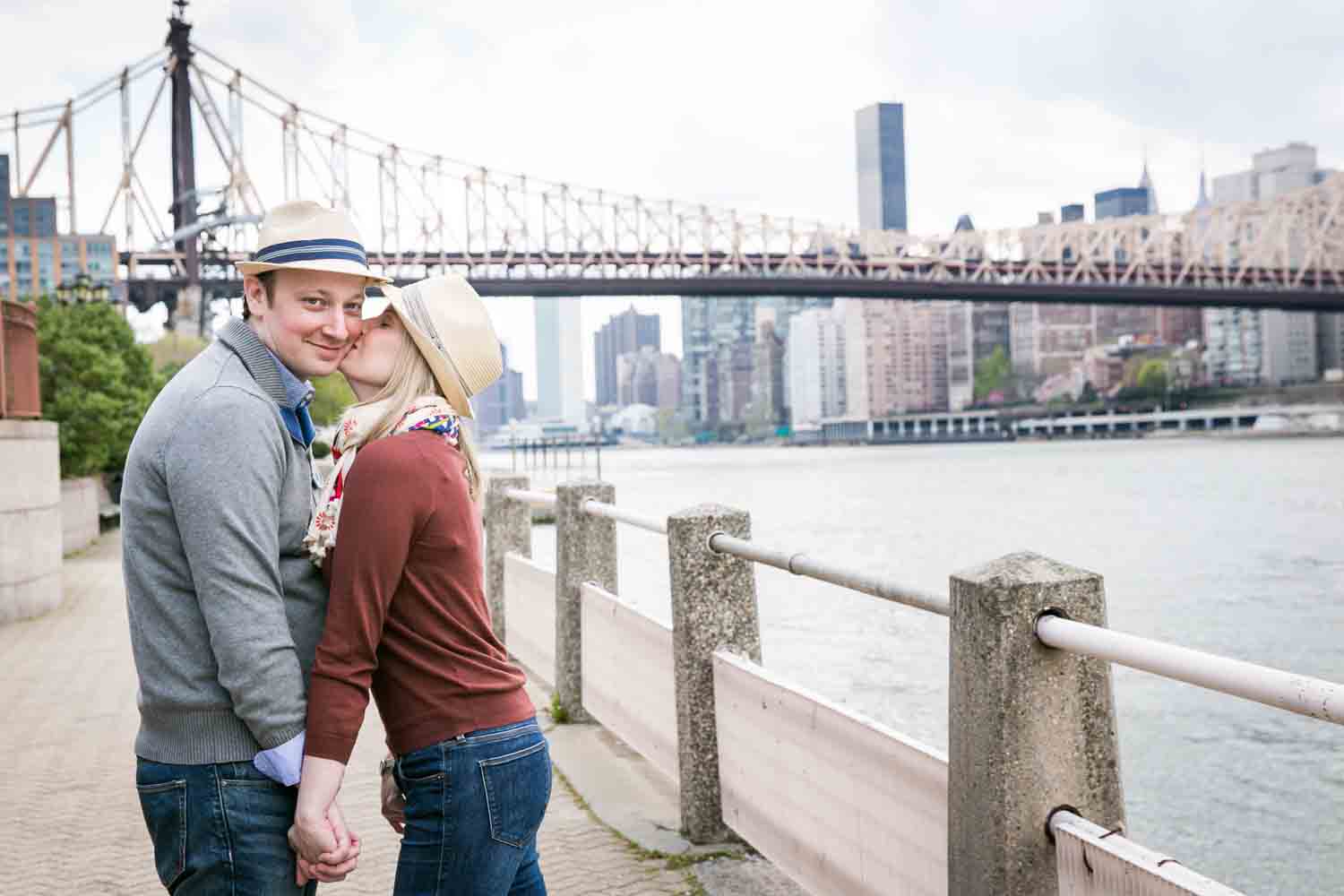 Woman kissing man on cheek during a Roosevelt Island engagement portrait session