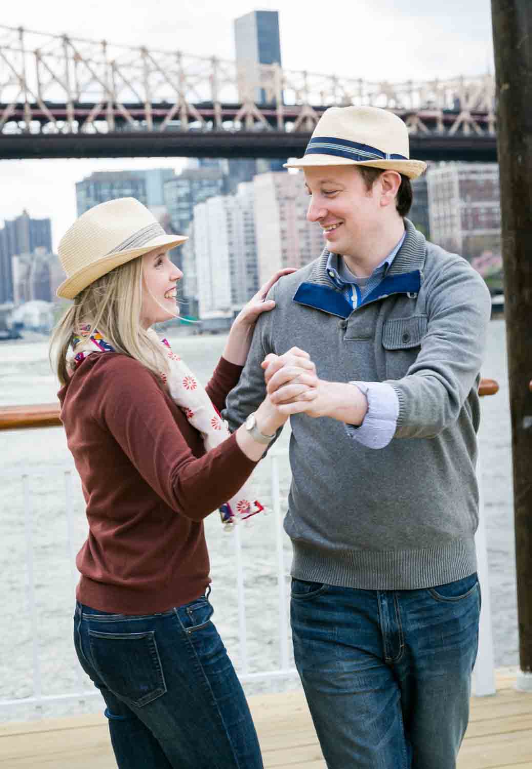 Couple dancing with Queensborough Bridge in background during a Roosevelt Island engagement portrait session