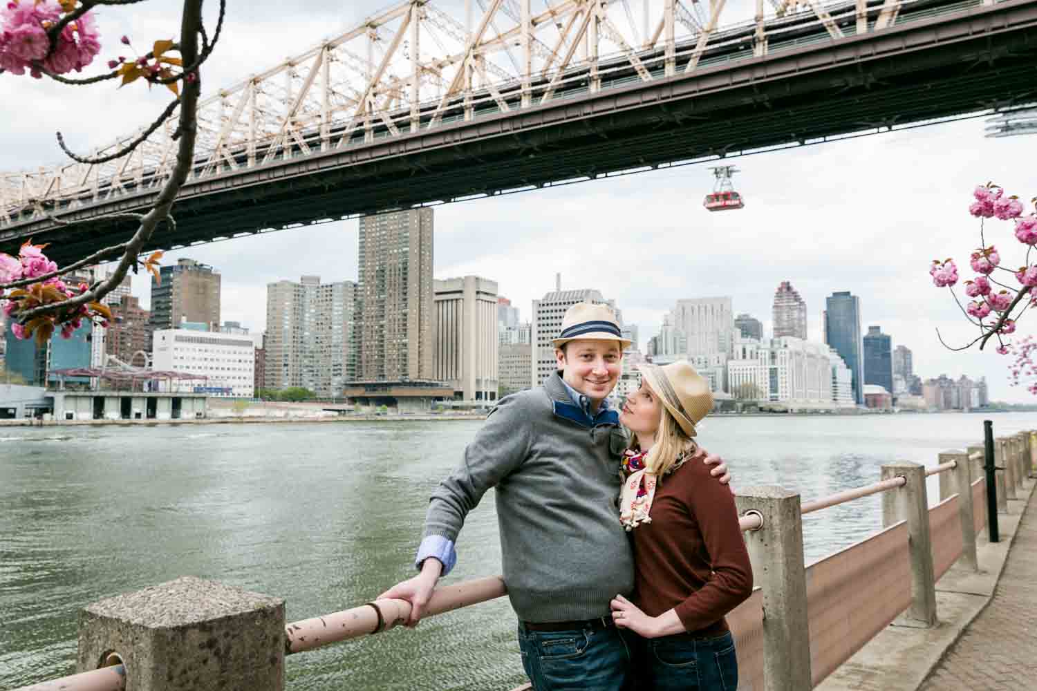 Couple against railing with Roosevelt Island tram in background