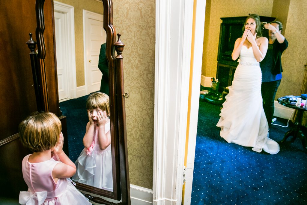 Bride getting ready and flower girl touching face in other room