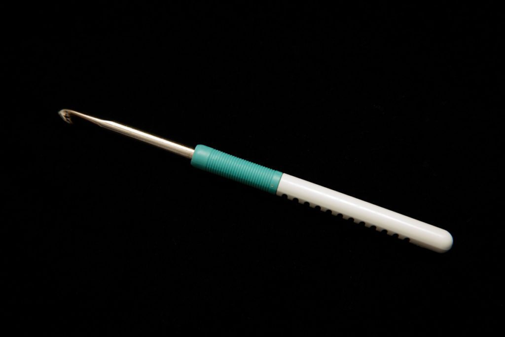 Crochet hook from a photography emergency kit on black background