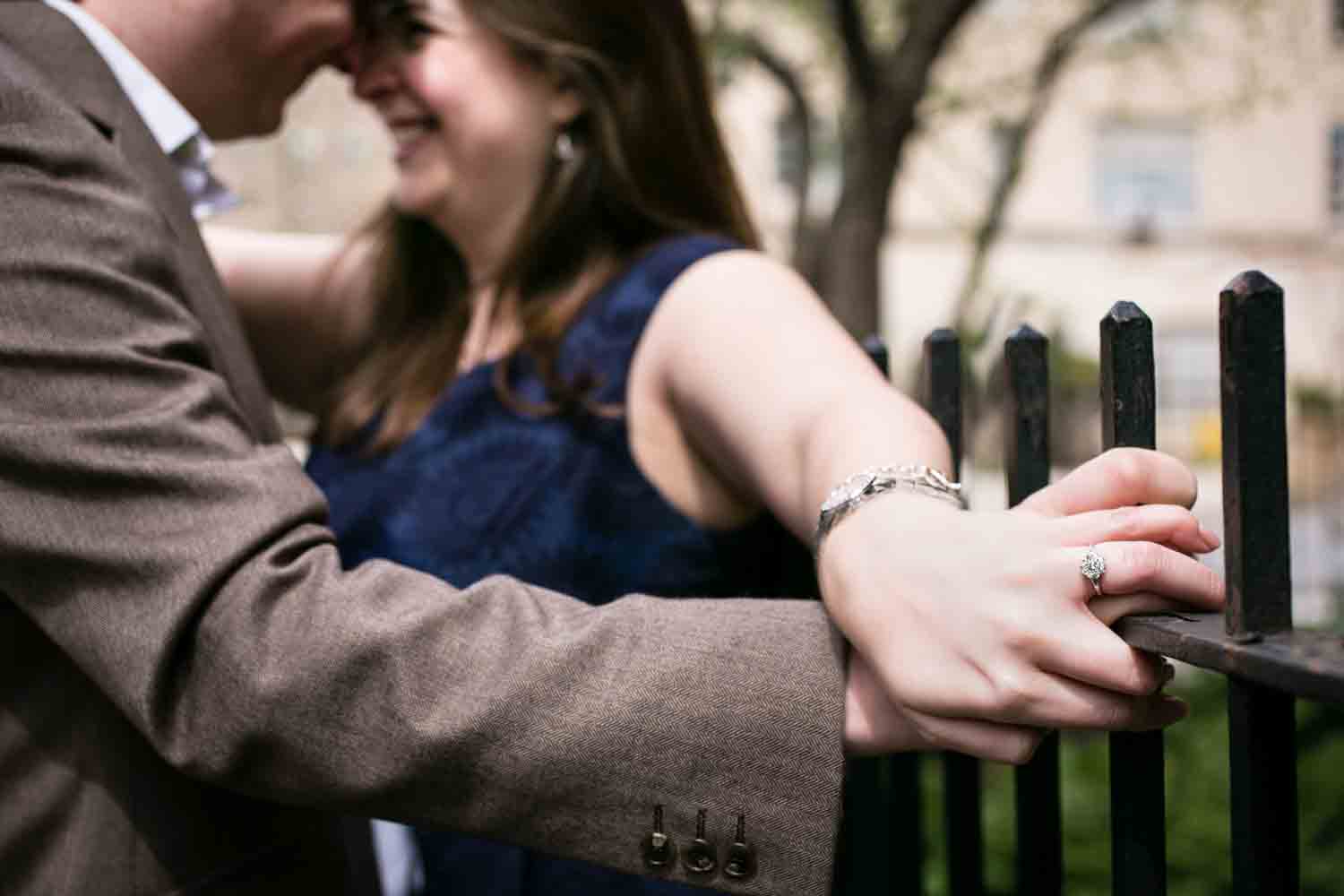 Close up on couple holding hands against fence railing