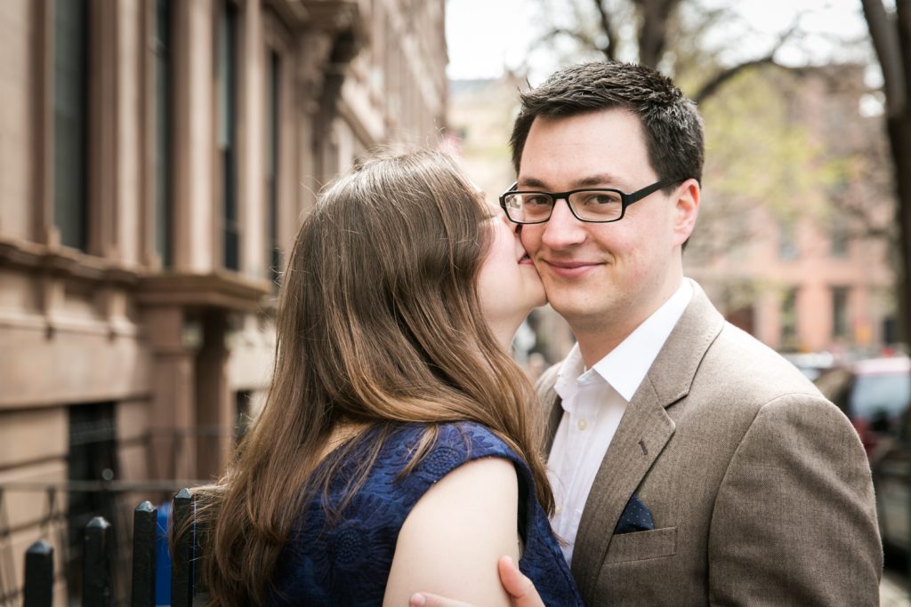 Woman kissing man wearing glasses on the cheek