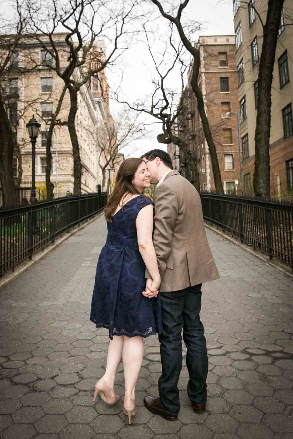 Couple walking down sidewalk and man kissing woman on cheek