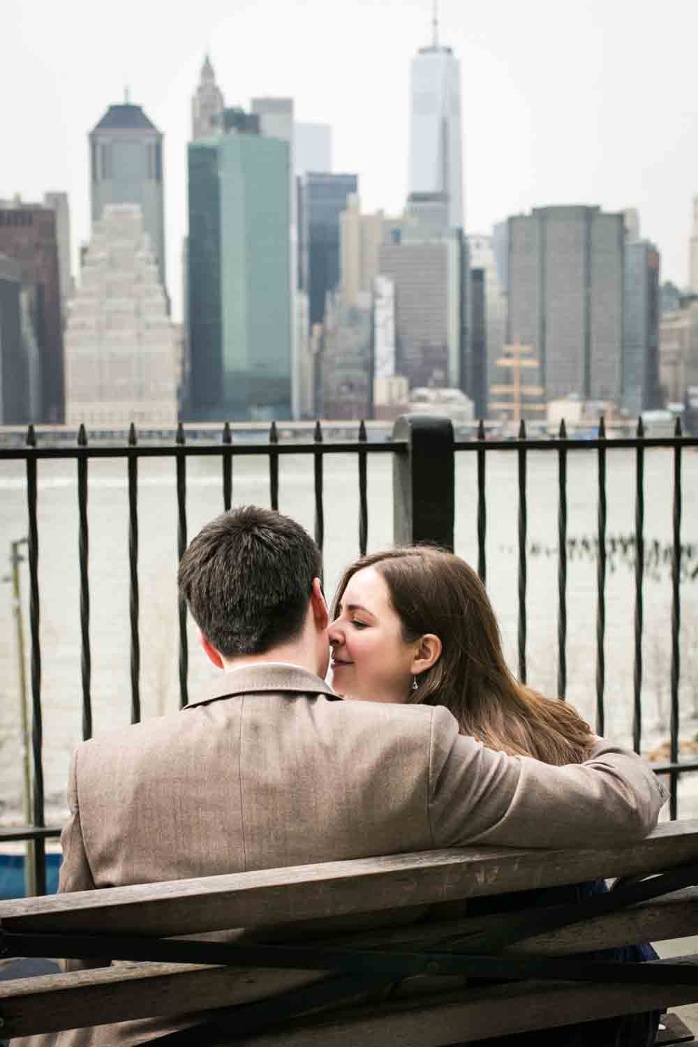 Couple sitting on bench on Brooklyn Promenade and woman kissing man on cheek