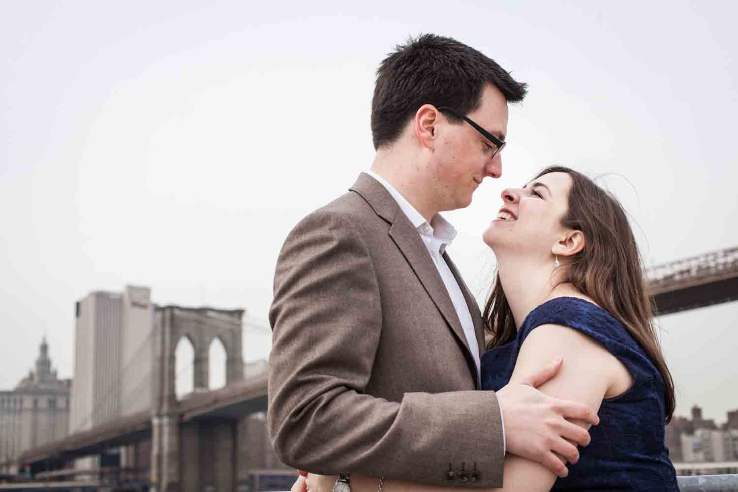 Brooklyn Promenade engagement photos of couple hugging with Brooklyn Bridge in background