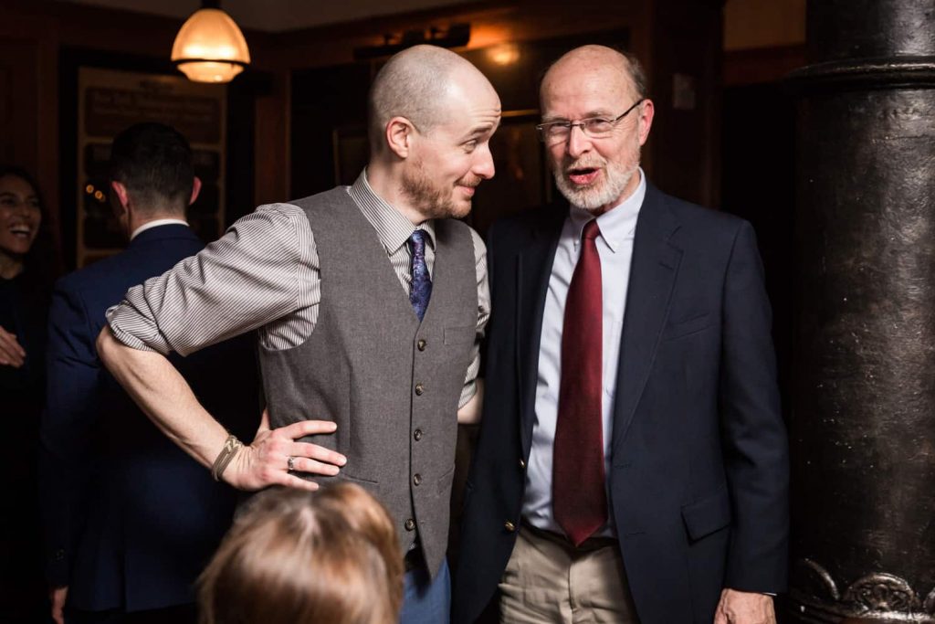 Groom talking with man during reception for an article on what is wedding photojournalism