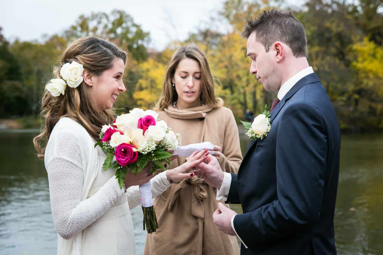 Groom putting ring on bride's finger at a Bethesda Fountain wedding in Central Park