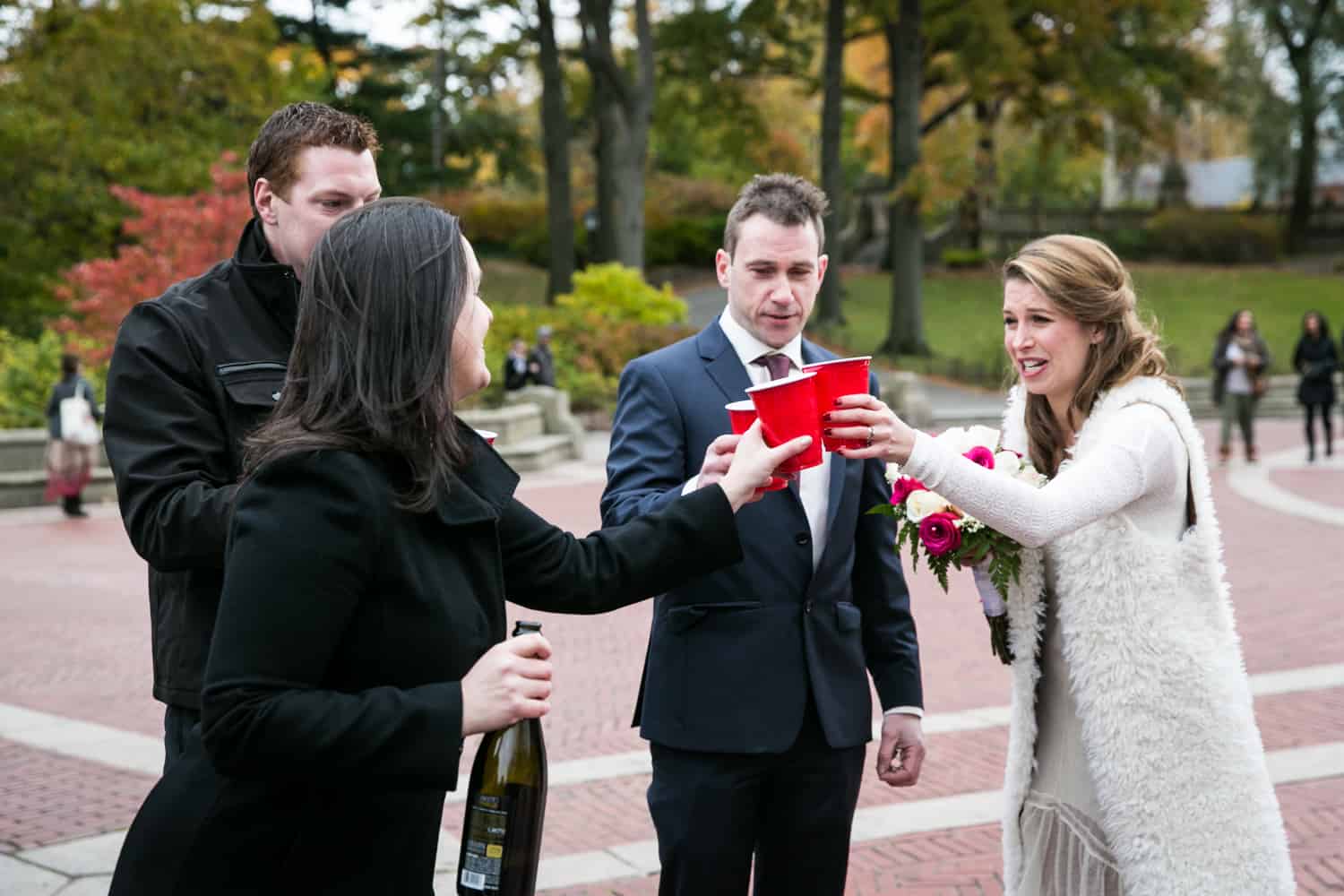 Bride, groom, and guests toasting with red plastic cups