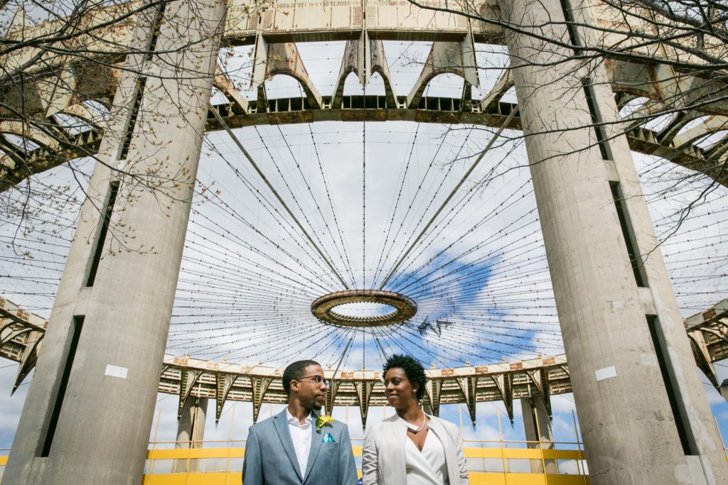 Portrait of bride and groom under world's fair architecture in Flushing Meadows Corona Park