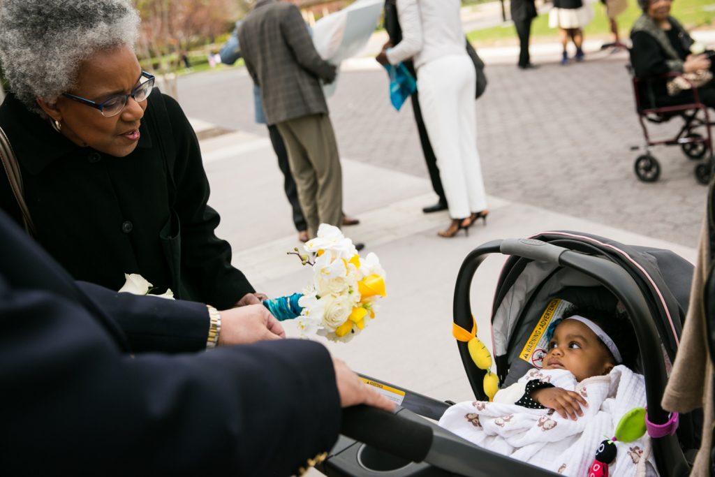 Baby in carriage looking at grandmother at a Flushing Meadows Corona Park wedding
