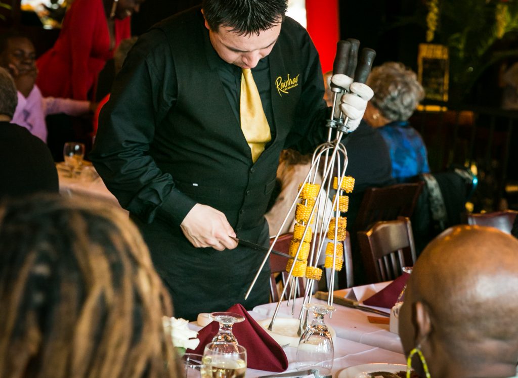 Waiter selecting piece of grilled pineapple