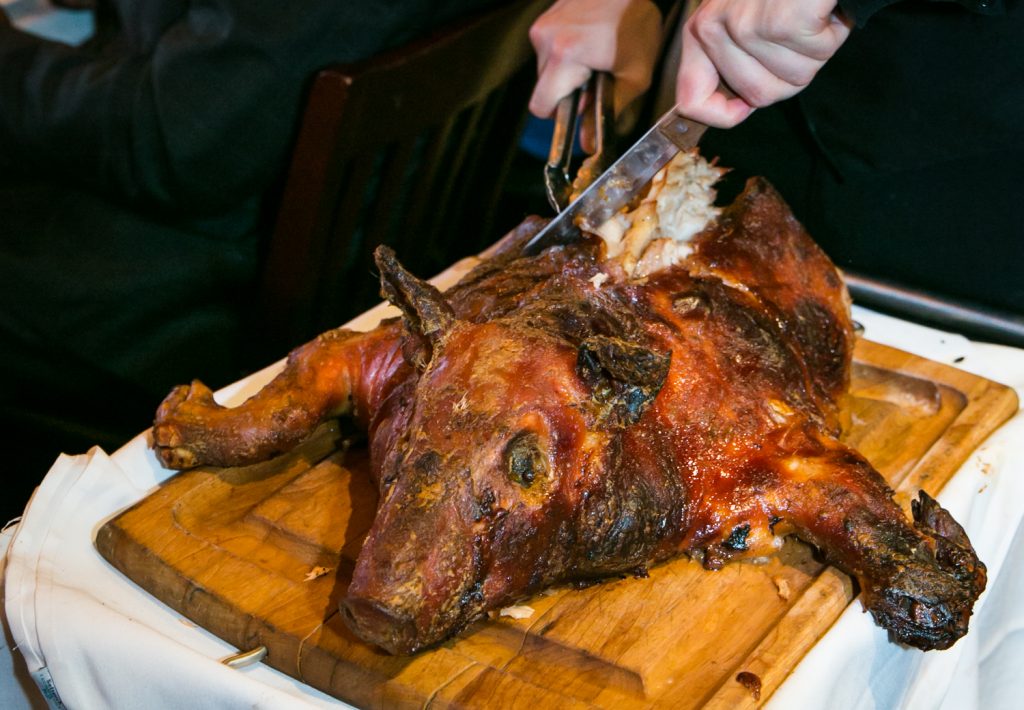 Close up of waiter cutting roast pig