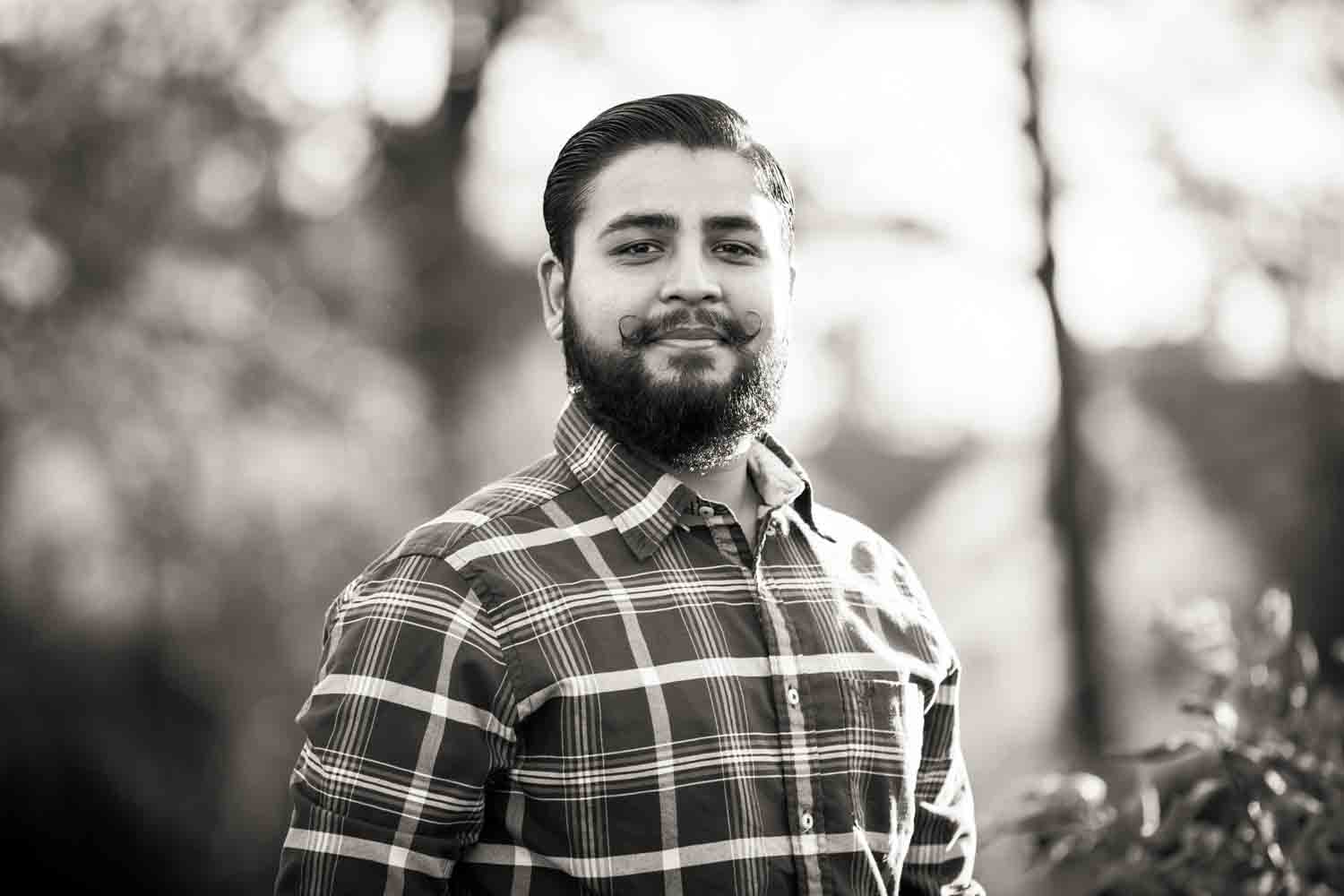 Black and white photo of man with moustache wearing plaid shirt