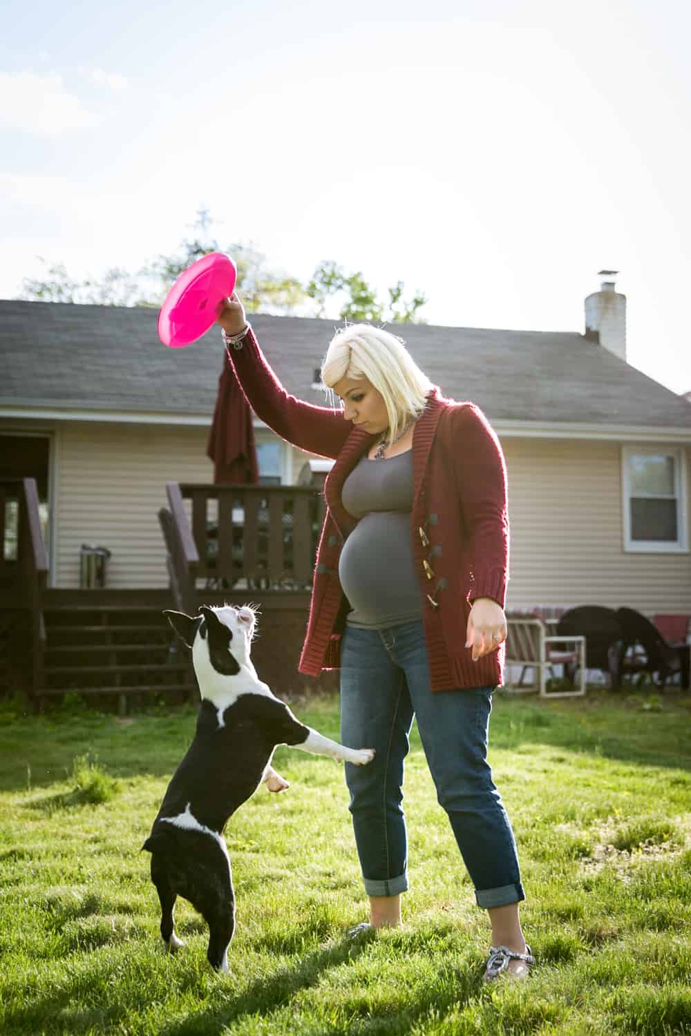 Pregnant woman playing with dog in backyard