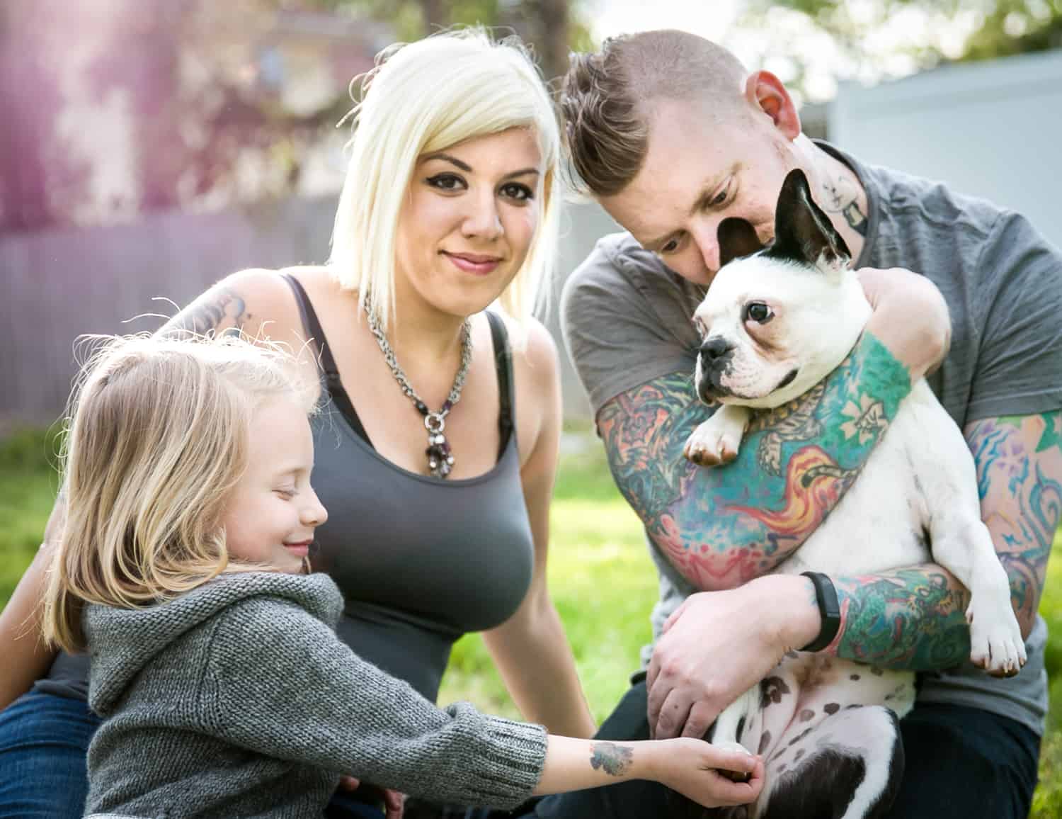 Pregnant woman, man, young girl and dog in backyard
