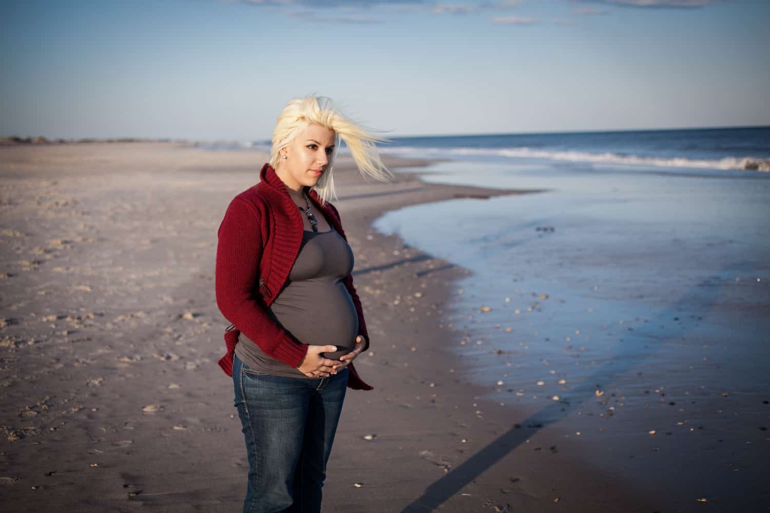 Pregnant blond woman on beach for an article on how to prepare for a maternity photo shoot