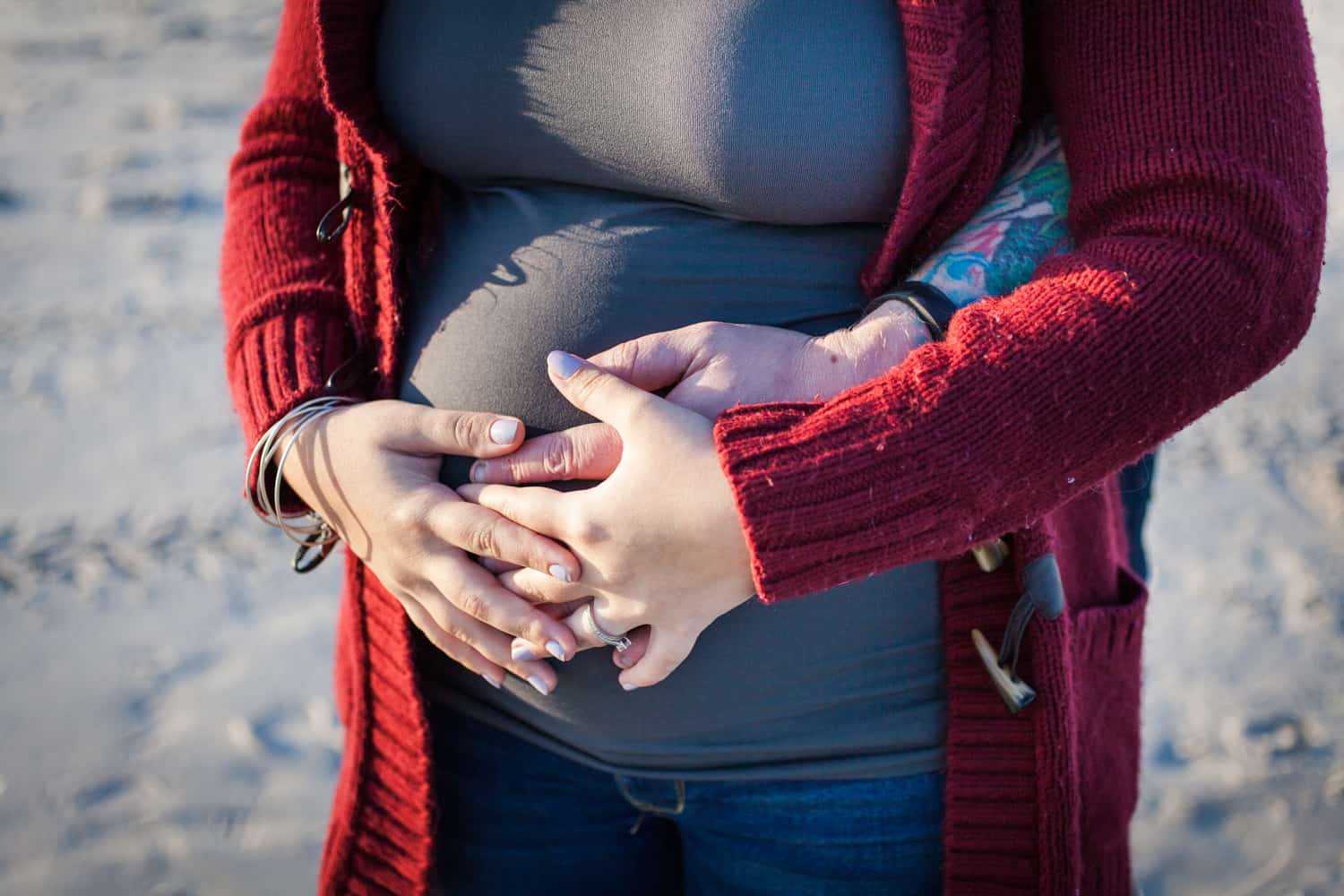 Close up of two pairs of hands on pregnant woman's stomach
