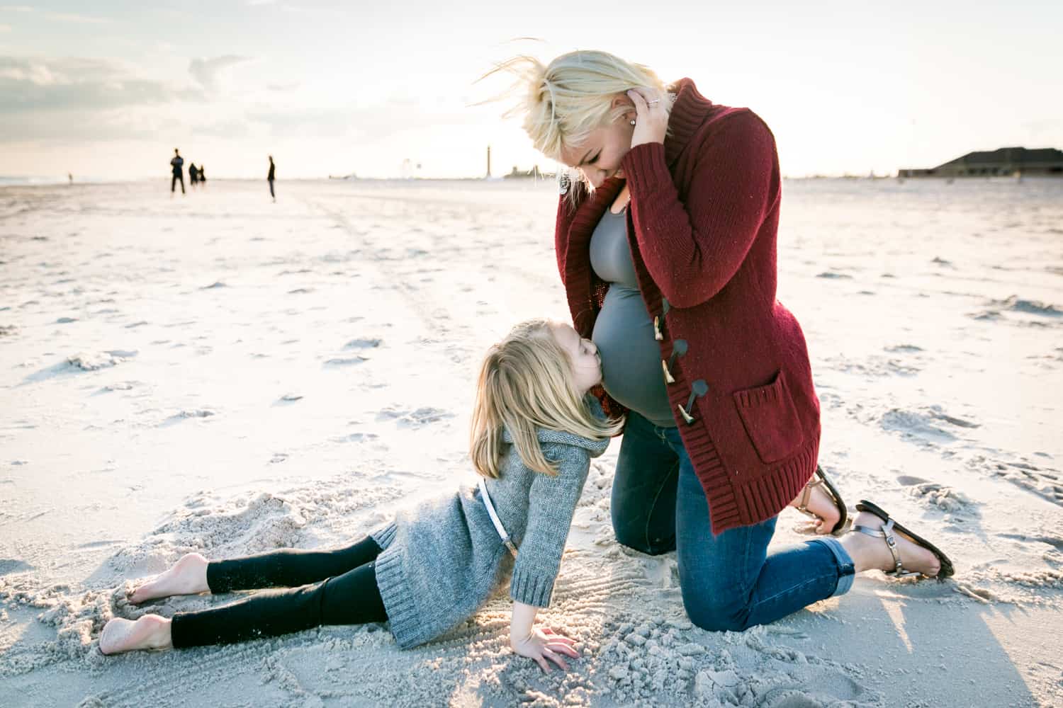 Little girl kissing blond pregnant woman's stomach