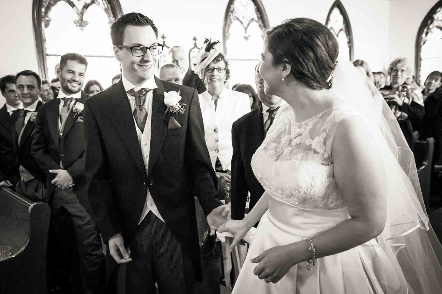 Black and white photo of bride and groom seeing each other for the first time in front of altar