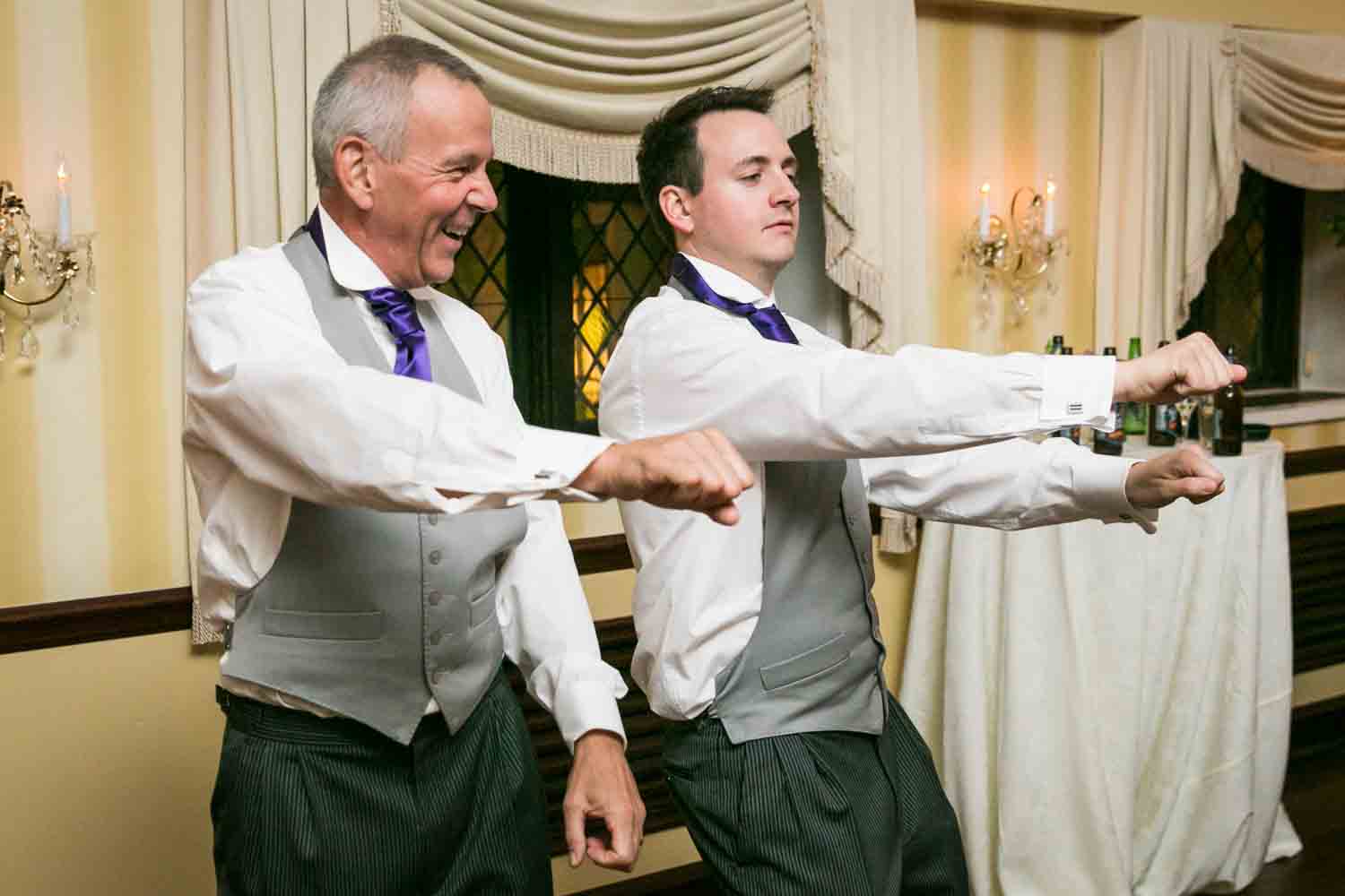 Two guests dancing at wedding reception with arms outstretched