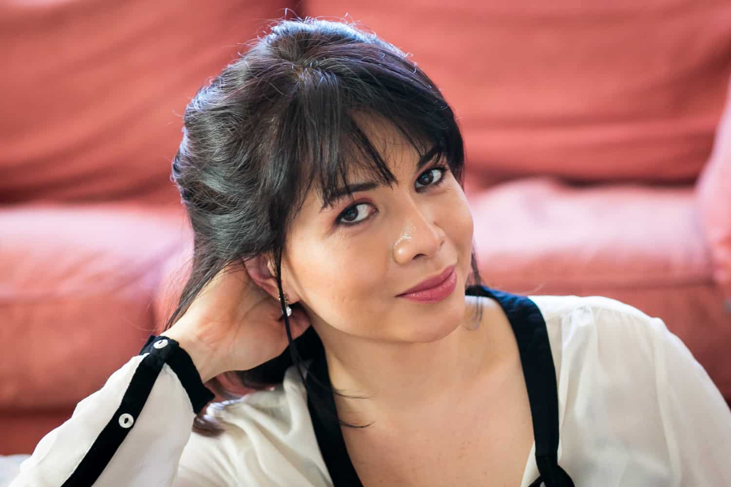 Woman with short black hair wearing black and white blouse