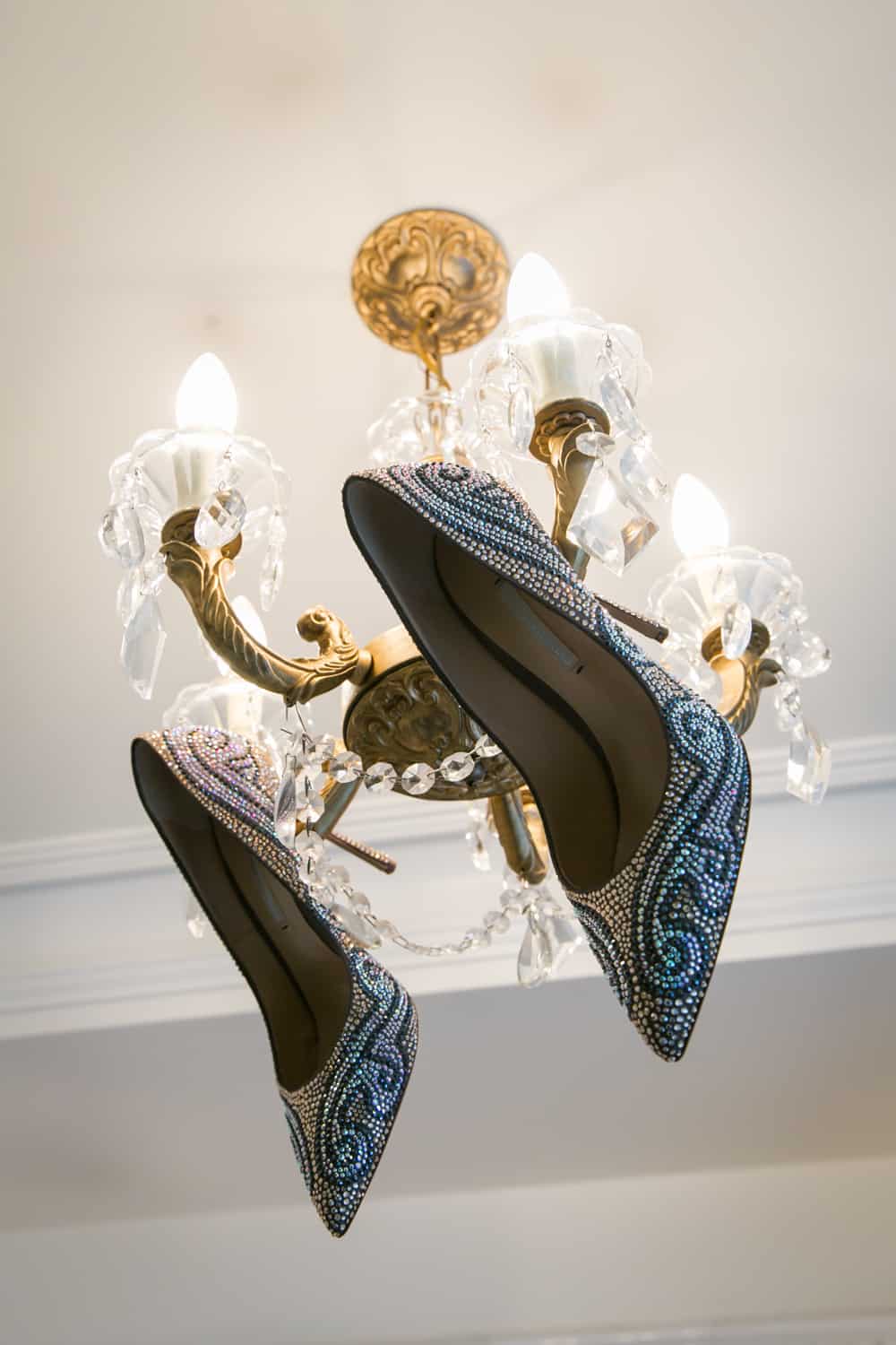 Sequined high heels hanging off a chandelier