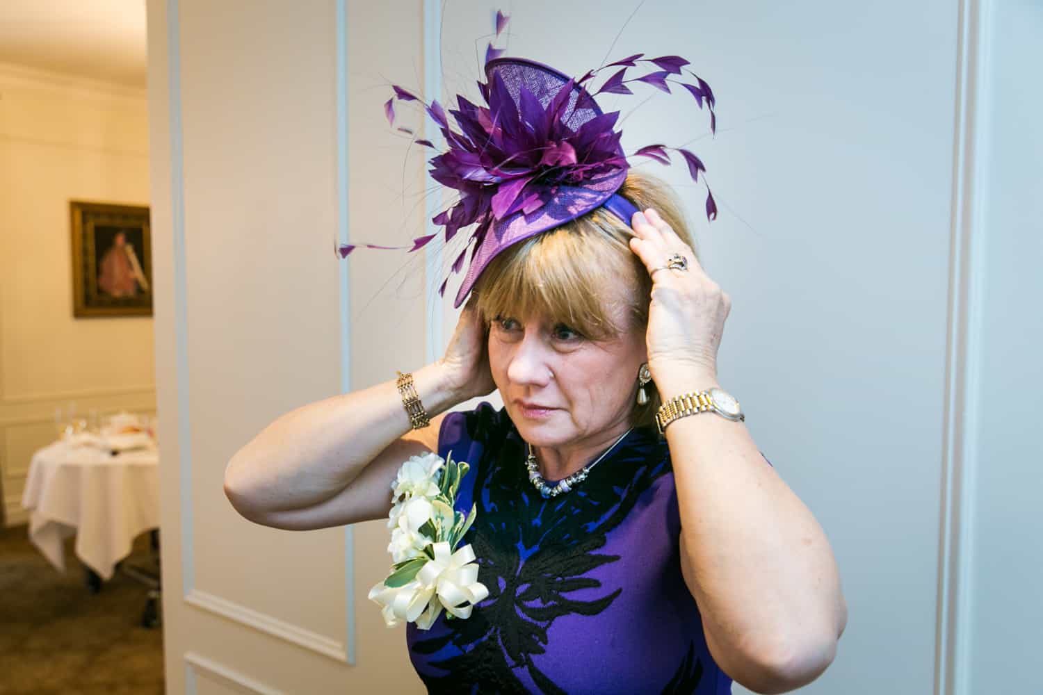 Woman adjusting purple hat before wedding