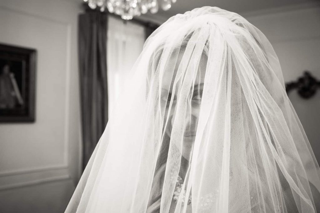 Black and white photo of bride looking through veil