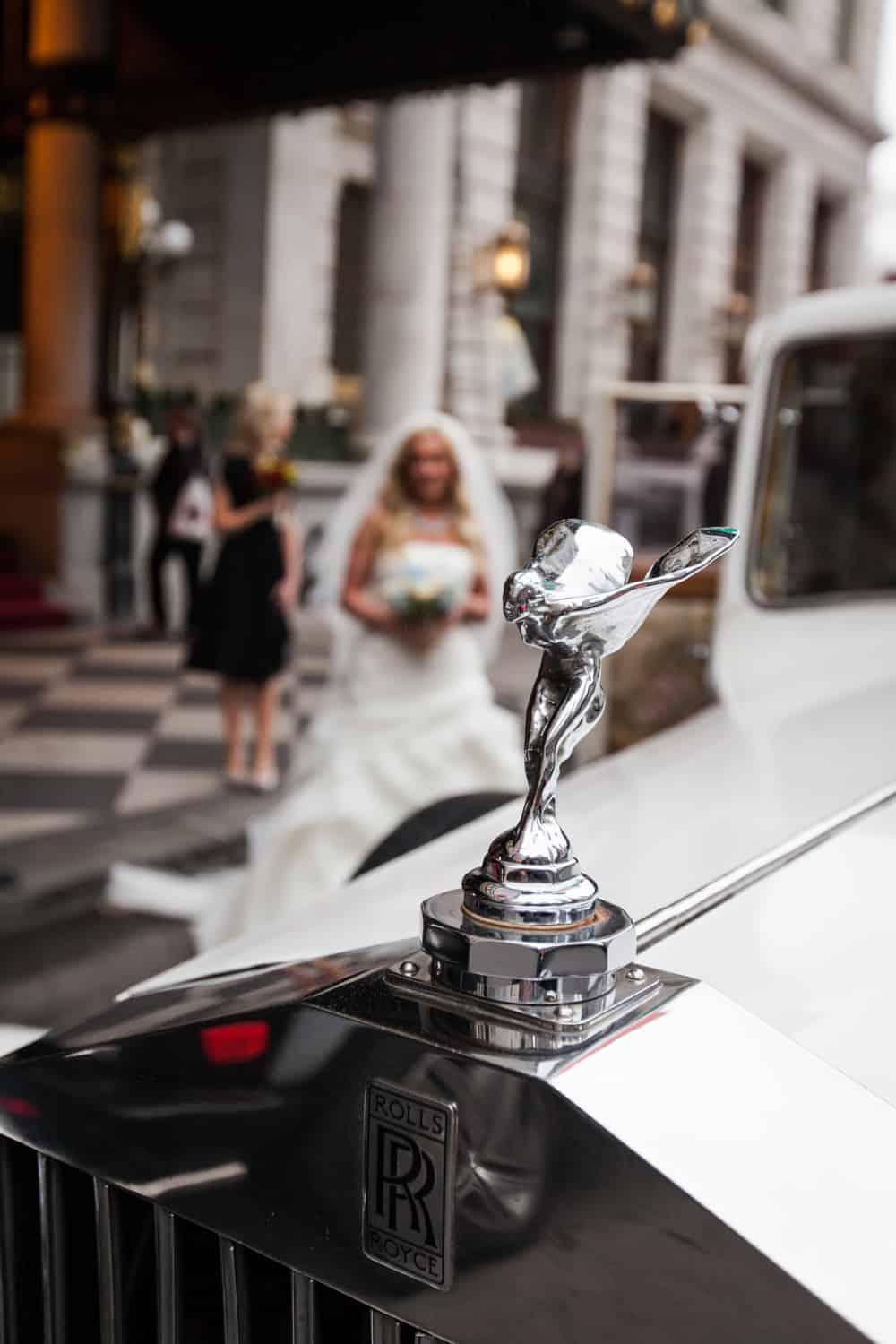 Rolls Royce car mascot with bride in background