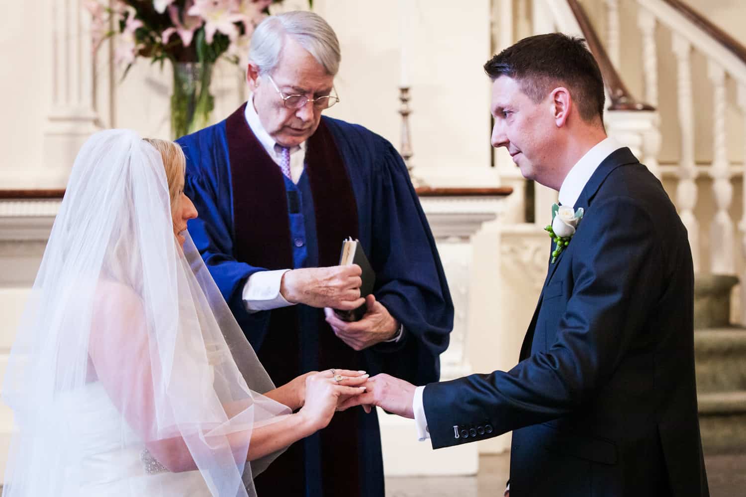 Bride putting ring on groom's finger during All Souls Unitarian Church ceremony