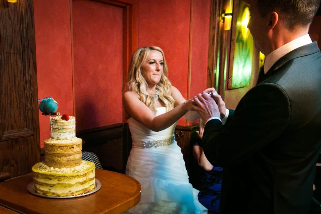 Bride pointing knife at groom with wedding cake at a Bergdorf Goodman wedding reception