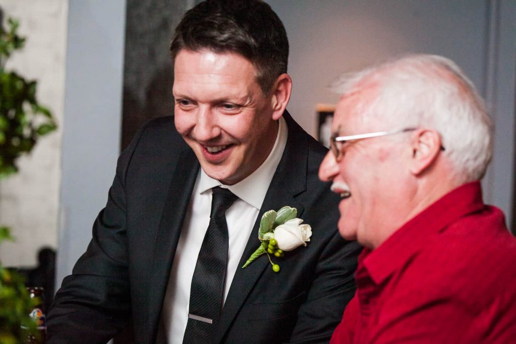 Groom laughing with older male guest