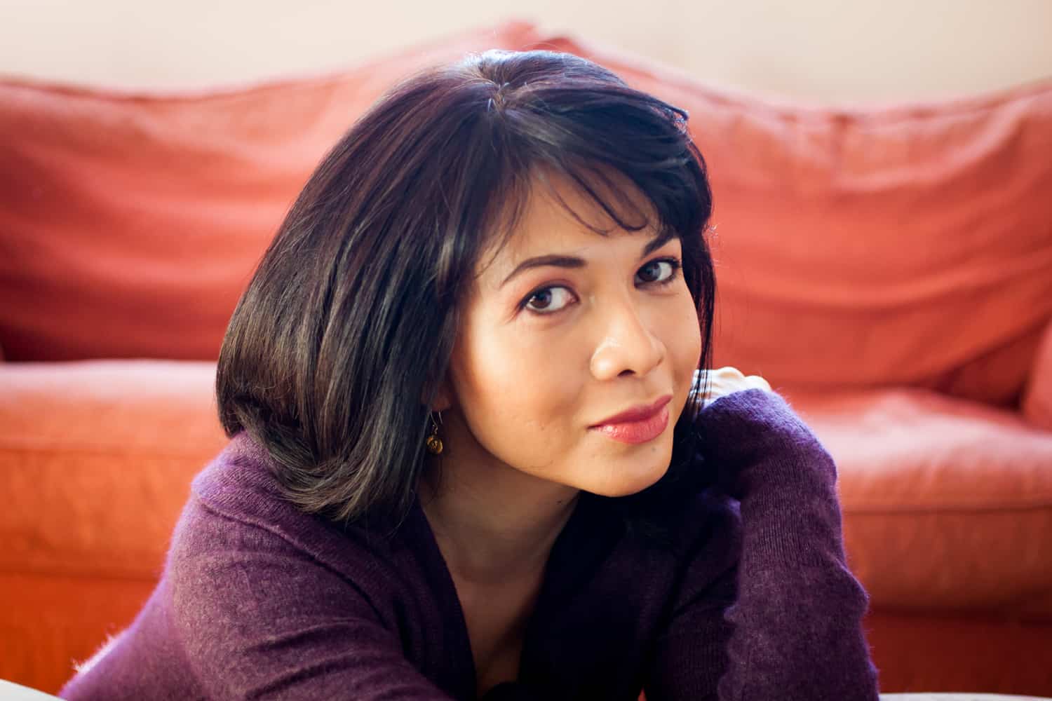 Woman with short black hair wearing purple sweater for an article on how to look slimmer in photos