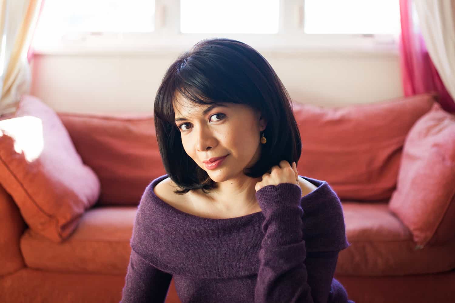 Woman with short black hair wearing purple sweater for an article on how to look slimmer in photos