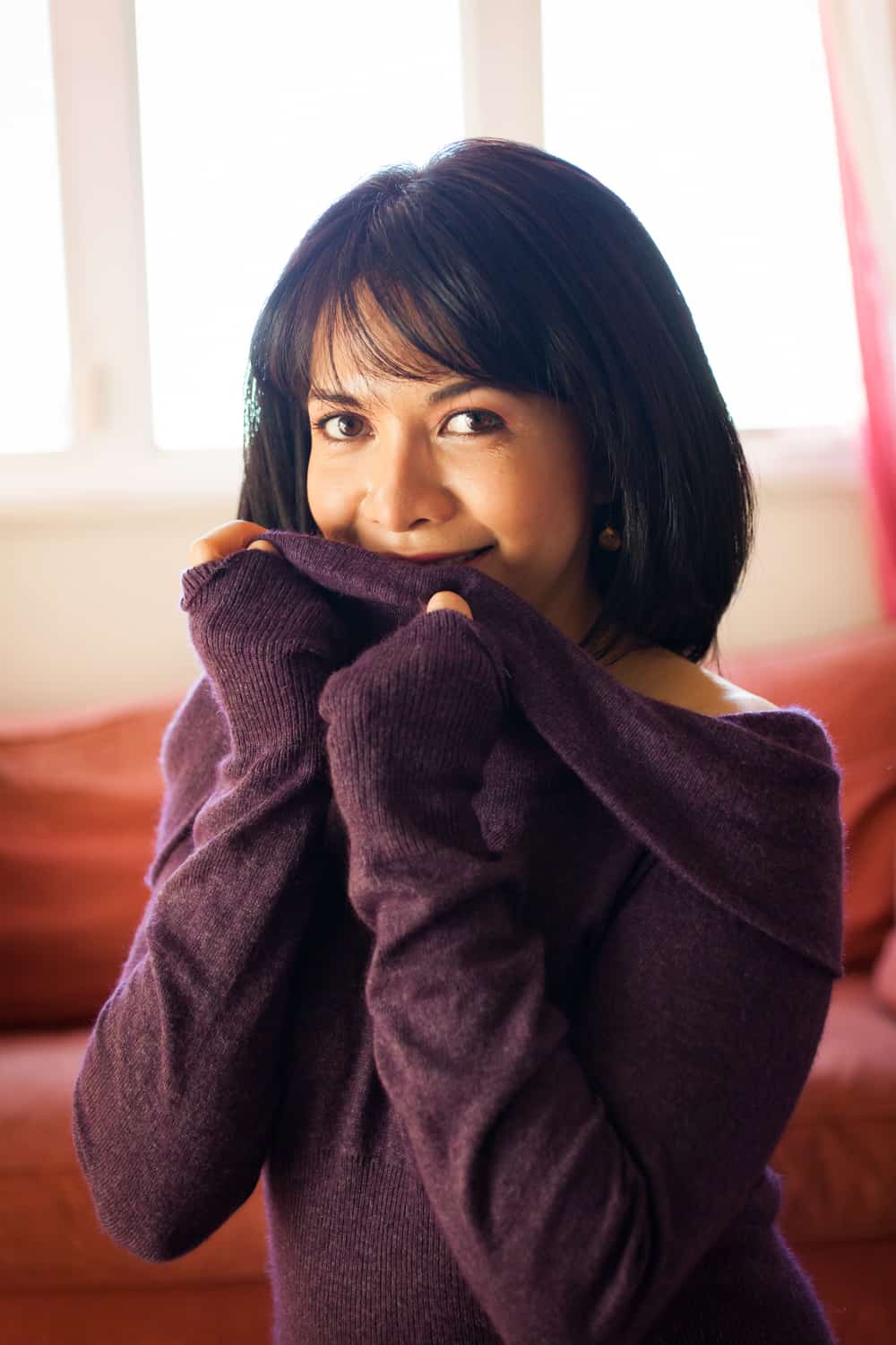 Woman with short black hair wearing purple off-shoulder sweater