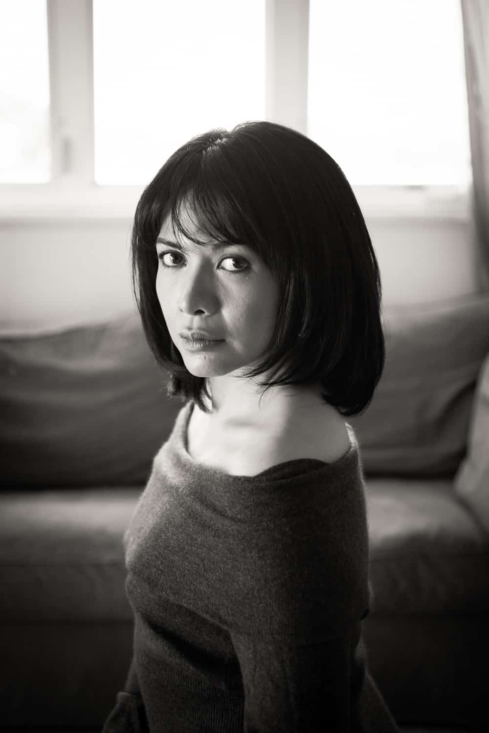 Black and white photo of woman with short black hair wearing off-shoulder sweater