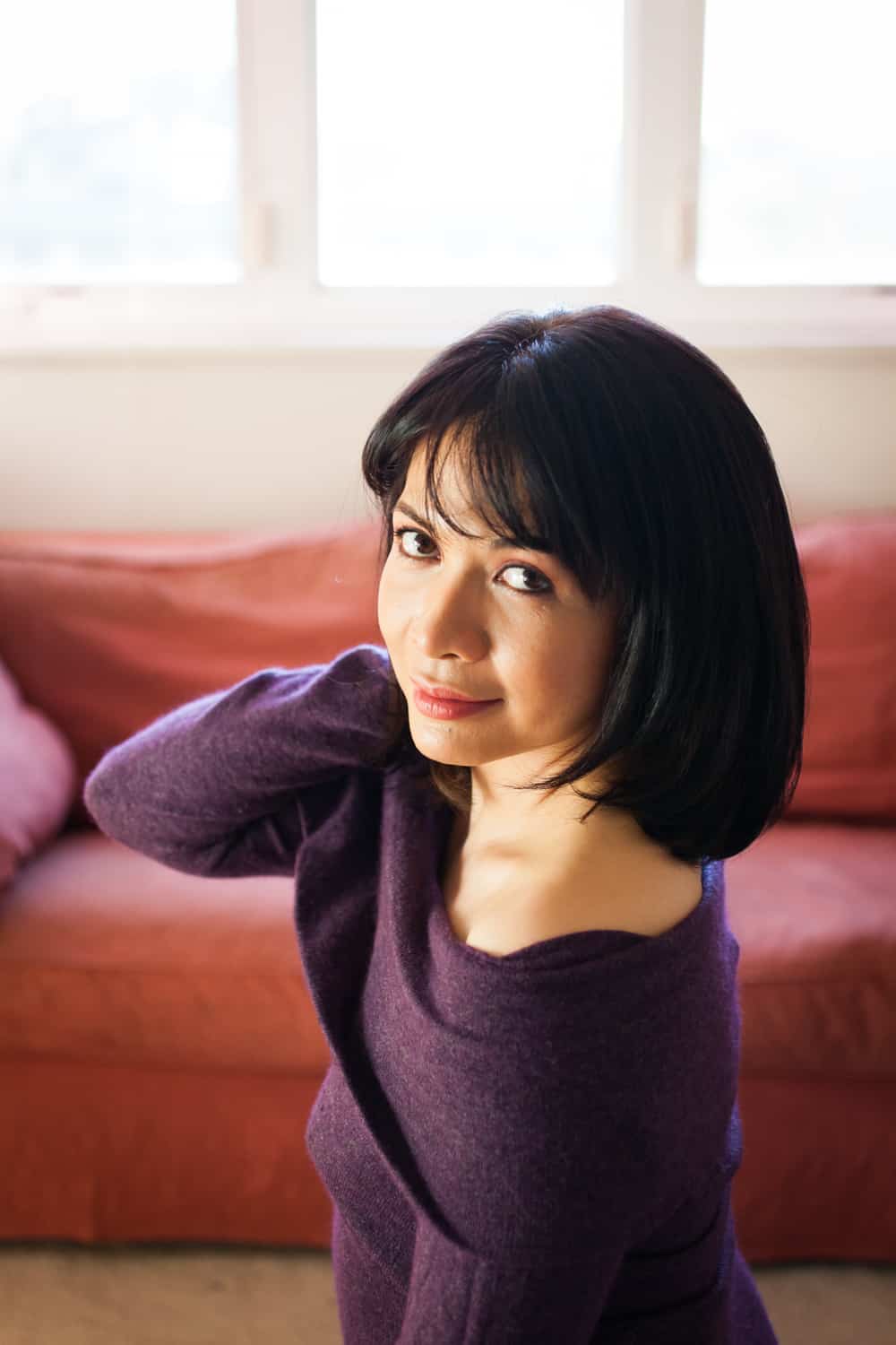 Woman with short black hair wearing purple off-shoulder sweater