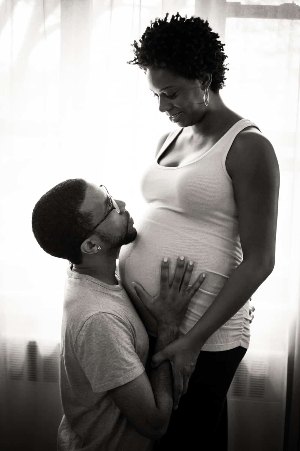 Black and white photo of father looking up at pregnant mother