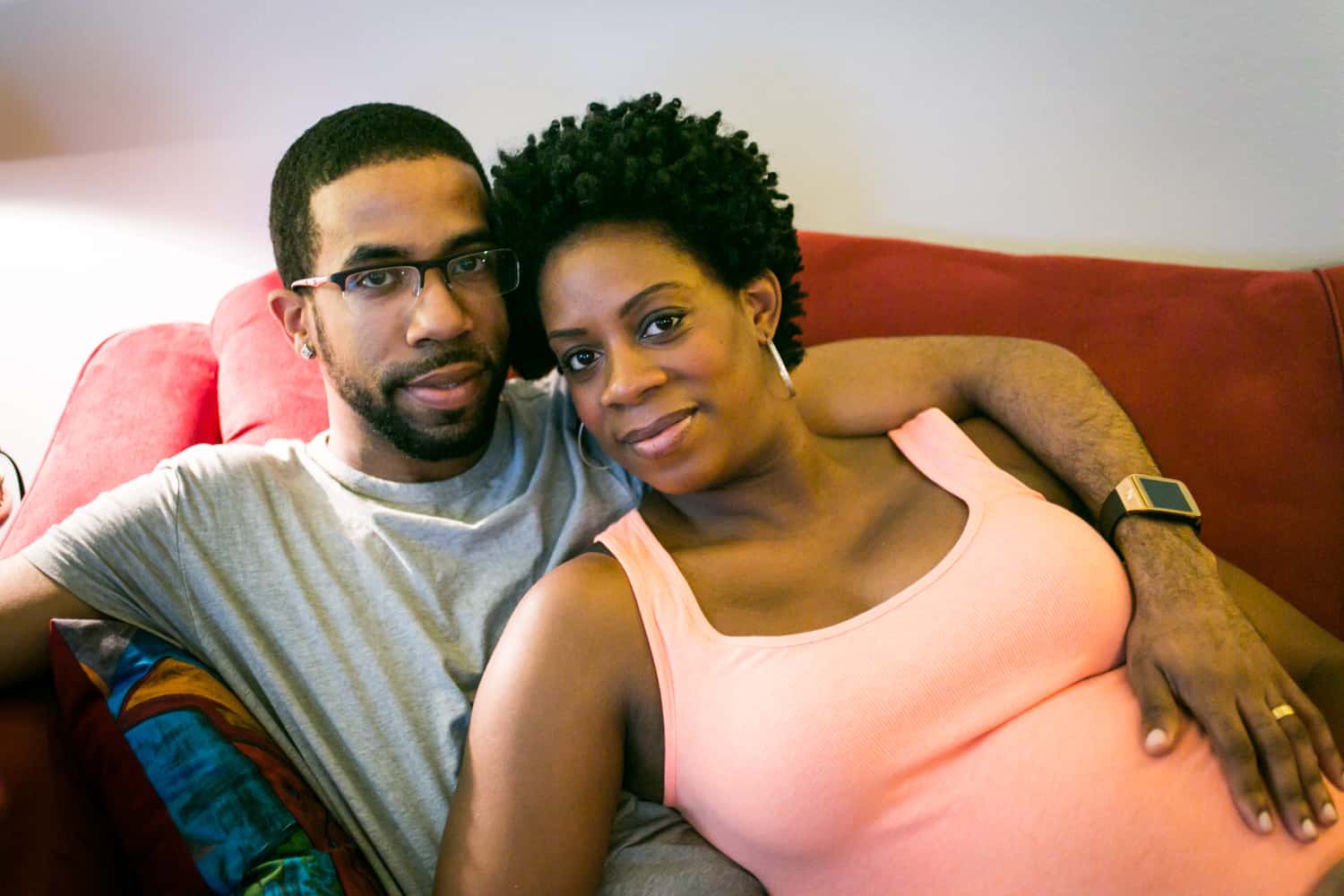 Parents-to-be sitting on couch by Queens maternity photographer