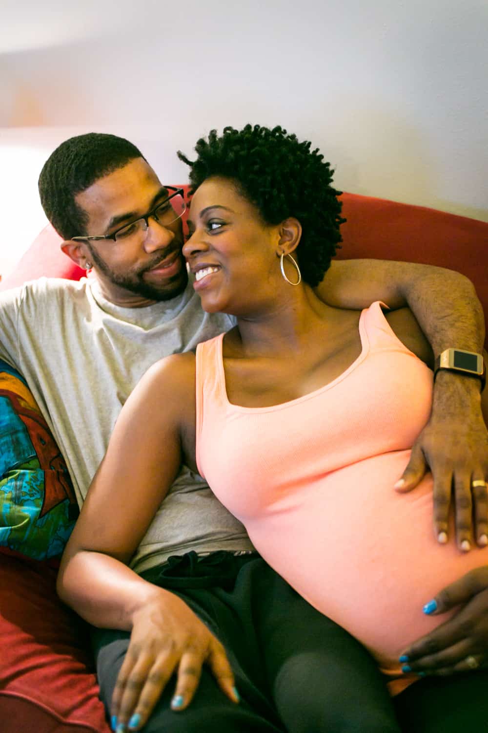Parents-to-be sitting on couch by Queens maternity photographer