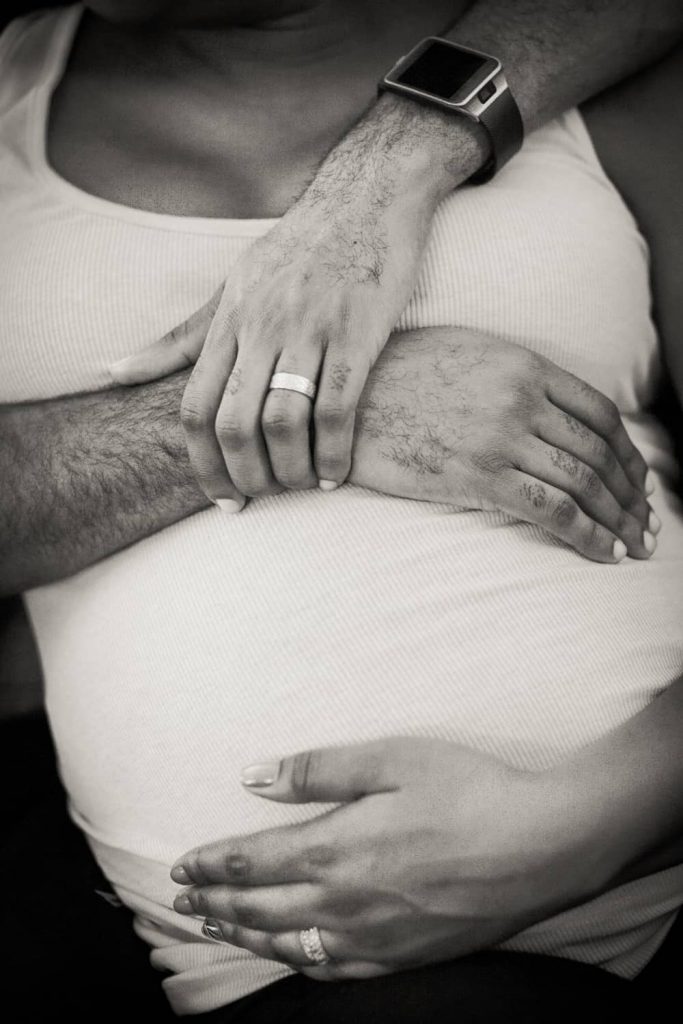 Close up of parents-to-be touching pregnant stomach by Queens maternity photographer