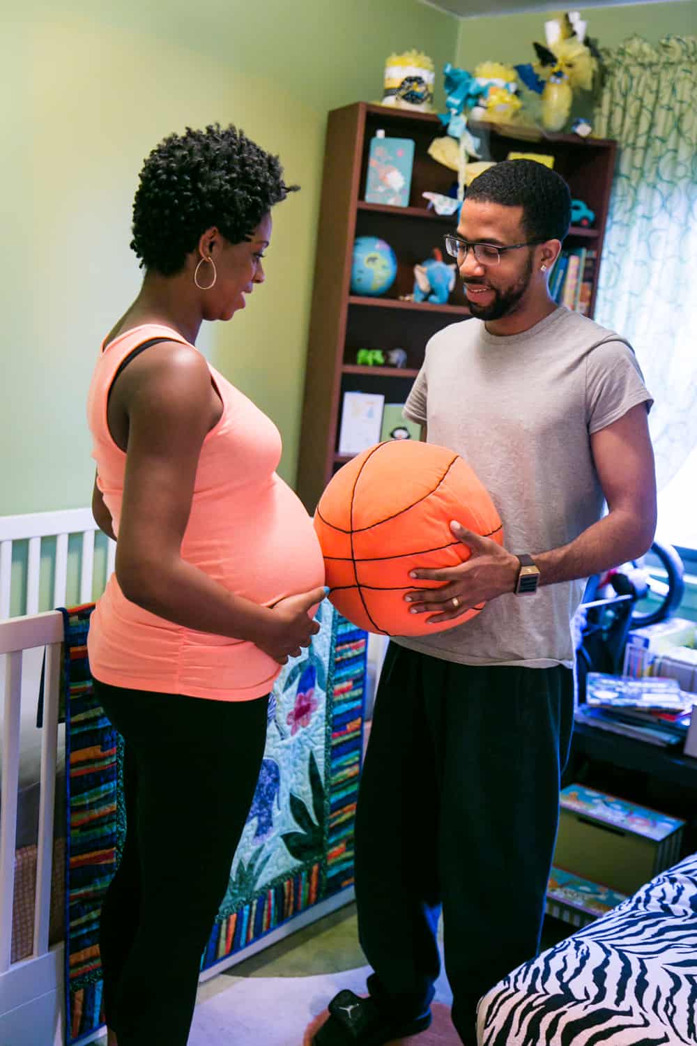 Parents-to-be comparing pregnant stomach to stuffed basketball by Queens maternity photographer