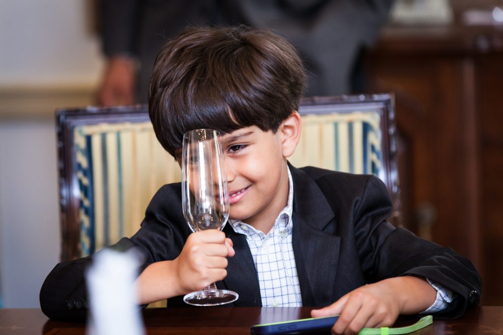 Little boy playing with champagne glass at a Waldorf Astoria wedding
